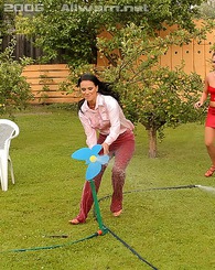 Two hot lesbian babes playing with a garden hose outside